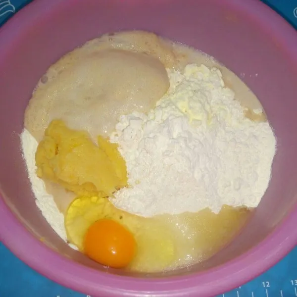 Di wadah campur tepung terigu, susu bubuk, tape, telur, gula pasir, dan bahan biang. Aduk rata lalu uleni sampai setengah kalis