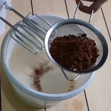 Lalu tambahkan coklat bubuk dan tepung terigu sambil diayak. Lalu mixer kembali sampai rata, masukkan larutan coklat dan minyak lalu aduk menjadi 1 menggunakan spatula