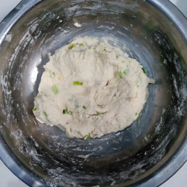 Kemudian siram ke dalam tepung terigu,tepung tapioka dan daun bawang. Aduk rata. Uleni sampai kalis.