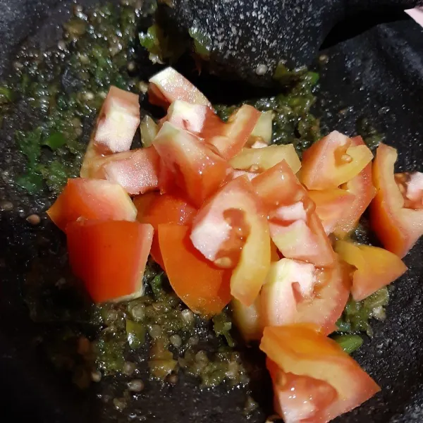 Tambahkan potongan tomat ke dalam ulegan sambal, aduk rata.