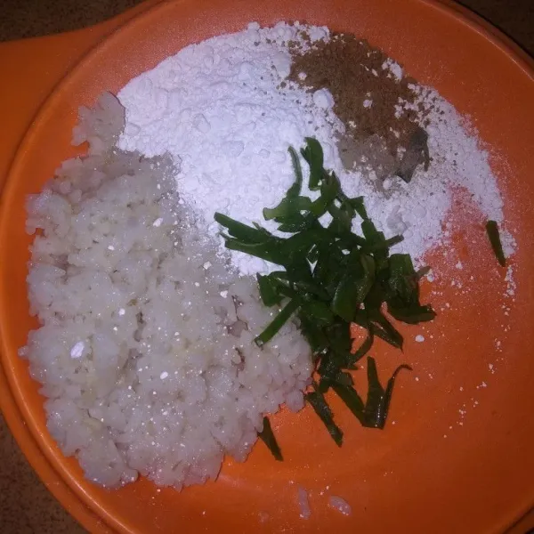 Siapkan wadah, campur nasi yang telah dihaluskan, tambahkan tepung kanji, irisan bawang daun, lada bubuk, dan penyedap rasa