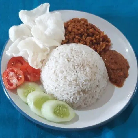 Penyelesaian : Siapkan piring saji. Cetak nasi dengan menggunakan mangkuk kecil, tata di atas piring saji, tuang beberapa sendok kering tempe, tambahkan sambal goreng terasi dan kerupuk, lalu tata beberapa potong timun dan tomat. Nasi uduk magicom siap dihidangkan.