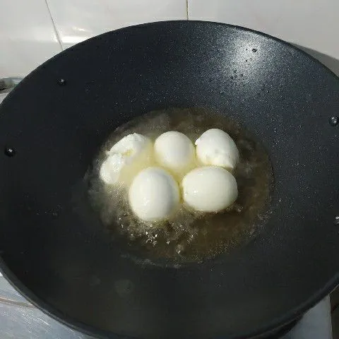 Rebus telur, kupas kemudian goreng sampai berkulit.