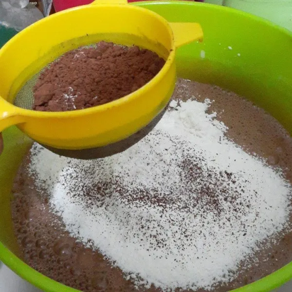 Masukan tepung terigu, coklat bubuk, dan baking powder ke dalam adonan. Disarankan untuk diayak terlebih dahulu agar tepung dan lain-lainnya halus.