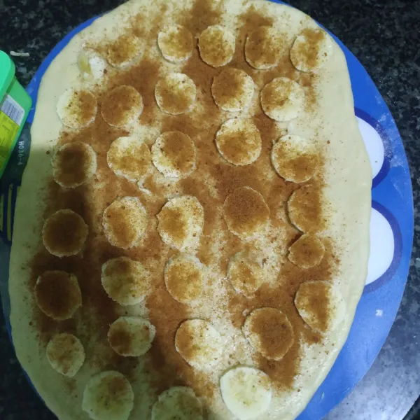 Beri olesan mentega di atas adonan. Potong-potong pisang dan taburi brown sugar.