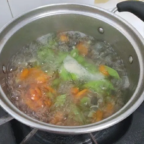 Didihkan air, rebus wortel sampai setengah matang. Tambahkan buncis, rebus sampai sayuran empuk.