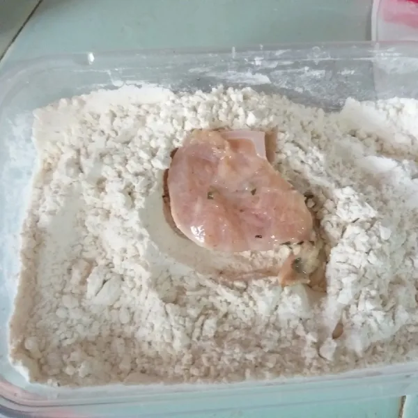 Lumuri ayam di atas tepung hingga terbalut sempurna.
