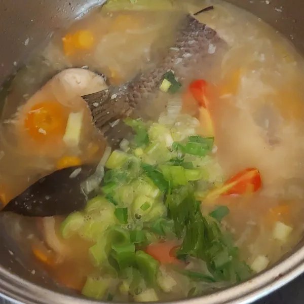 Setelah hampir empuk wortel masukan potongan tomat dan daun bawang ke dalam rebusan ikan gabus tunggu sampai wortel empuk.