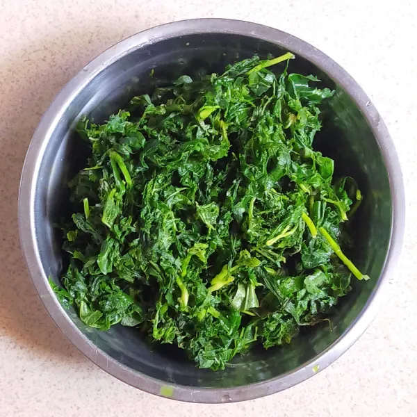 Siapkan tumbukan, lalu siapkan satu ikat daun singkong. Lalu tumbuk kasar dengan alat penumbuk lalu sisihkan.