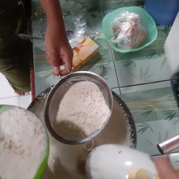 Setelah itu masukan tepung terigu bersama baking powder, sambil diayak agar tidak ada yang bergerindil, mixer sebentar sampai rata