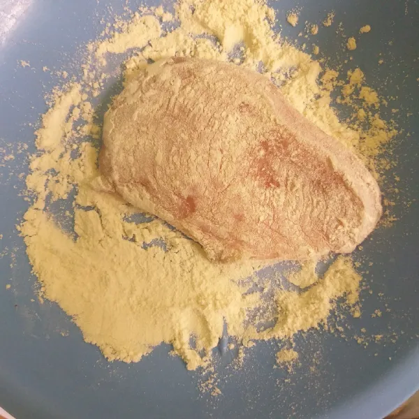 Ambil 1 bagian ayam, gulingkan ke tepung terigu sampai rata.