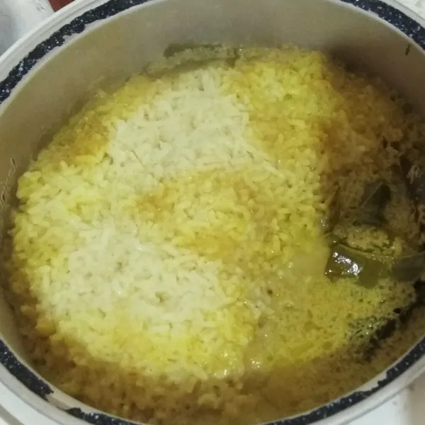 Setelah nasi kuning matang, segera di aduk nasi kuningnya (bumbu akan berada di permukaan nasi kuning). Aduk hingga tercampur rata. Tutup lagi magicom. Tunggu beberapa saat hingga nasi kuning tanak.