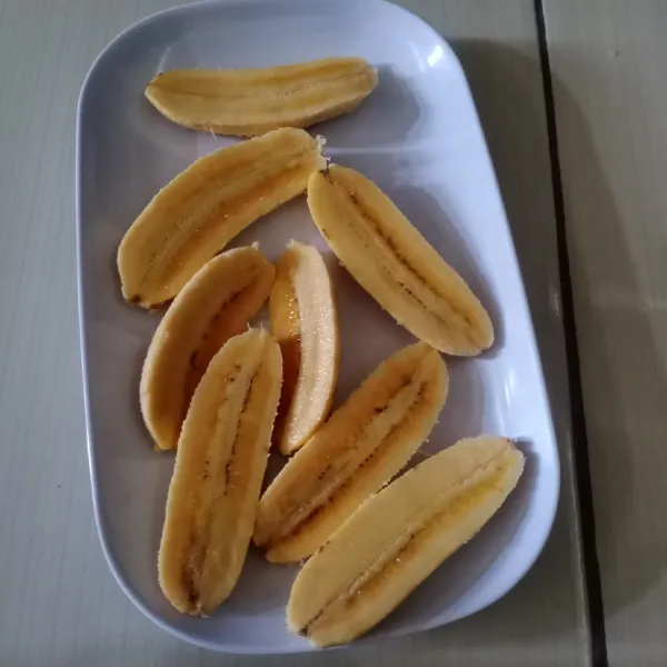 Kupas pisang kemudian belah menjadi 2 bagian.