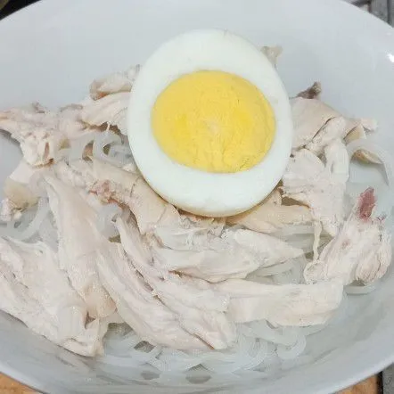 Tata bihun, suiran daging ayam beserta telur di mangkok siram dengan kuah panas & sajikan dengan pelengkap.