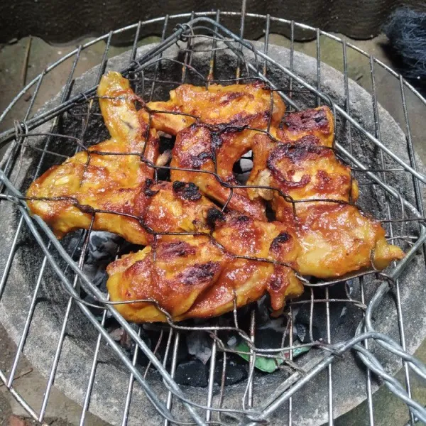 Proses memanggang ayam bakar dengan daun pisang