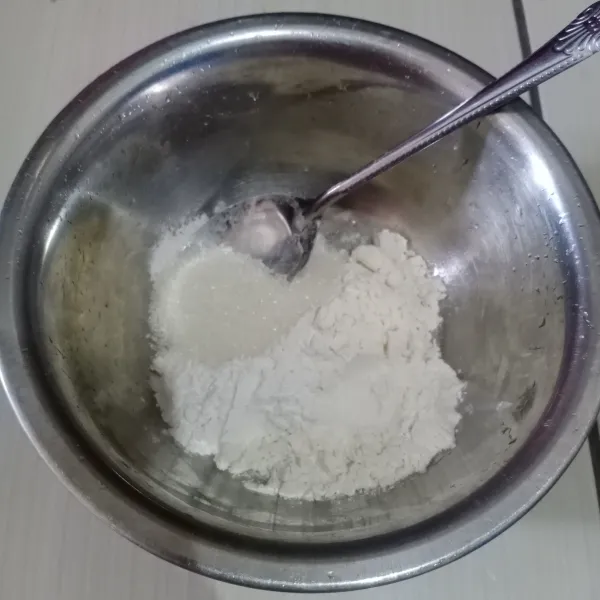 Dalam wadah campur terigu, tepung beras, gula pasir dan garam.