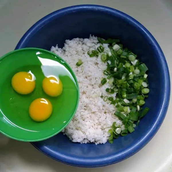 Siapkan wadah, masukkan nasi putih, daun bawang dan telur.