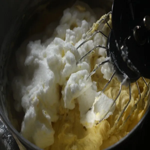 Setelah rata, campurkan sepertiga bagian kocokan putih telur ke dalam adonan, aduk rata dengan whisk, tuang sepertiga bagian selanjutnya, aduk, lanjut sisanya.