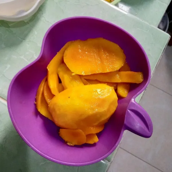 Cuci lalu kupas mangga, potong-potong.