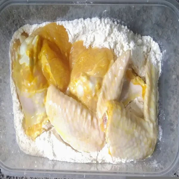 Siapkan tepung bumbu serbaguna dalam wadah, masukkan sayap ayam yang sudah di marinasi.