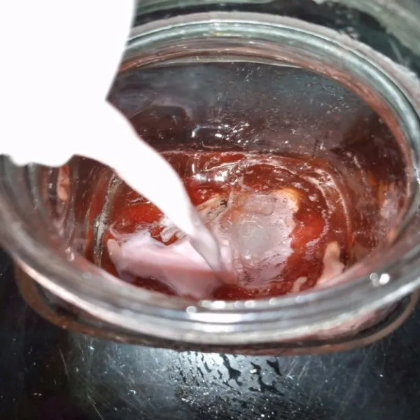 Masukkan es batu dalam gelas tambahkan strawberry selai tuang susu strawberry terlebih dahulu.