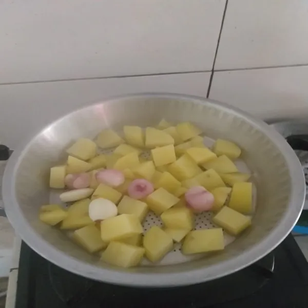 Kukus kentang yang sudah dipotong-potong, bawang merah dan bawang putih hingga matang.