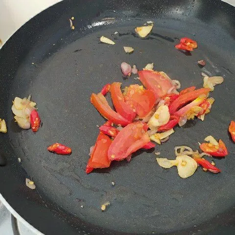 Tumis irisan bawang merah dan bawang putih sampai layu. Tambahkan irisan cabe rawit, cabe merah besar, tomat dan laos. Tumis semua sampai matang.