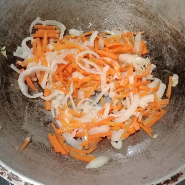 Tumis bawang putih sampai harum. Lalu masukkan irisan bawang bombay dan wortel tanpa air. Aduk rata.