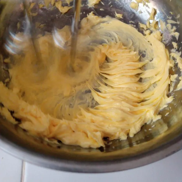 Mixer bahan C butter hingga berubah warna kemudian tuang susu kental manis.