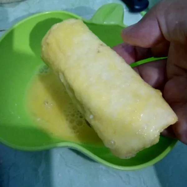 Celupkan pisang gulung dalam telur kocok.