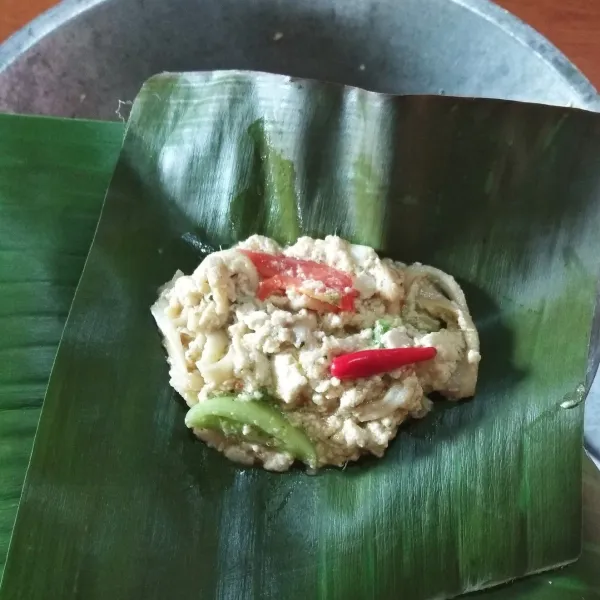 Ambil daun pisang. Panaskan di atas api kompor (di leumpeuh) biar daun pisannya mudah di bentuk dan ga sobek. Potong daun pisang sesuai dengan ukuran yang di inginkan. Masukkan sebanyak 2 sendok makan adonan pepes. Beri cabai rawit. Lalu dibungkus dan disemat dengan tusik gigi.