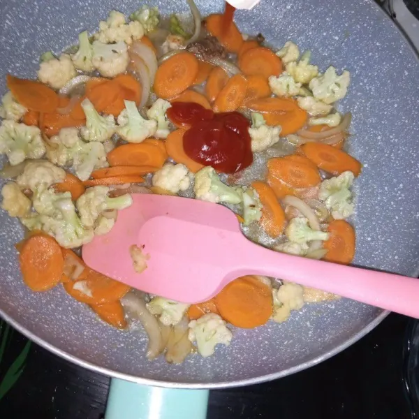 Masukkan wortel aduk rata, selang 2 menit masukkan kembang kol aduk rata. Biarkan 5 menit tambahkan 50 ml air tuang saus tomat garam, gula dan kaldu jamur.