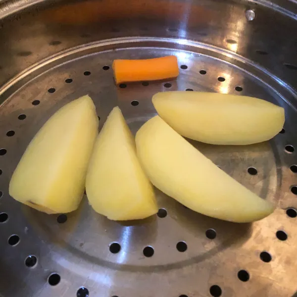 Kupas kulit kentang dan wortel, potong kentang, lalu kukus selama kurang lebih 30 menit. Setelah matang, tiriskan sebentar.