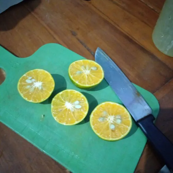 Siapkan jeruk, cuci dulu lalu potong jadi dua.