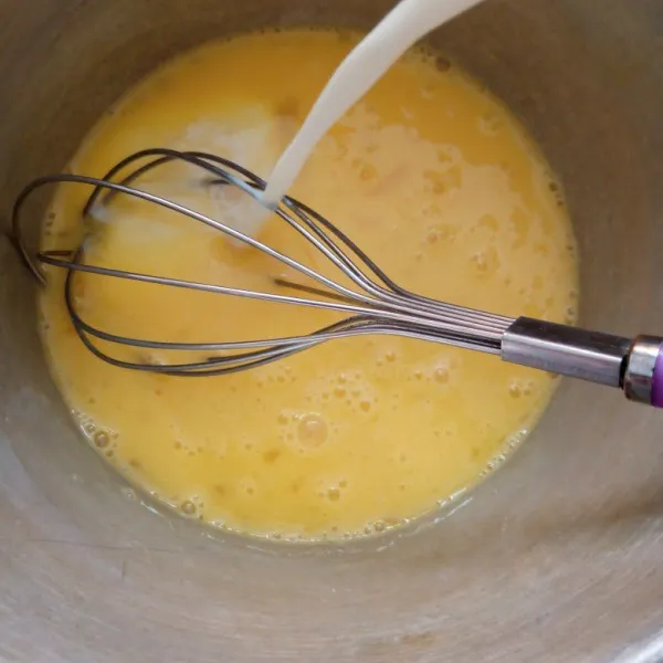 Kocok telur hingga rata menggunakan whisk aja tuang susu cair sambil diaduk.