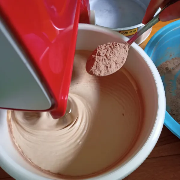 Turunkan speed, masukkan ayakan tepung terigu dan coklat bubuk sedikit demi sedikit. Matikan mixer.