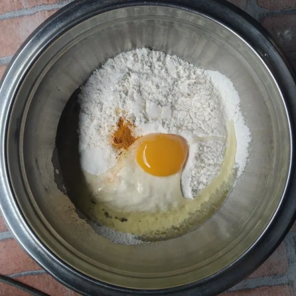 Ayak tepung terigu, masukan telur, garam dan kunyit bubuk, aduk rata.
