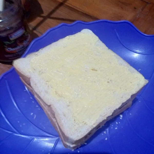 Tutup dengan selembar roti tawar yang terakhir dan olesi margarin di sisi atas dan sisi paling bawah.