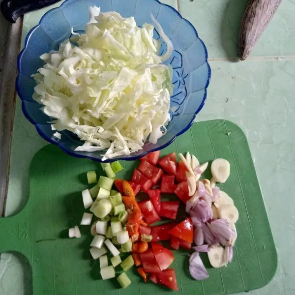 Rajang kasar kubis. Iris bawang merah, bawang putih, cabai rawit, tomat dan daun prei.