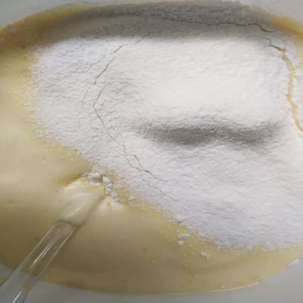 Masukan tepung terigu, susu bubuk, dan vanili bubuk secara bertahap sambil diaduk balik.
