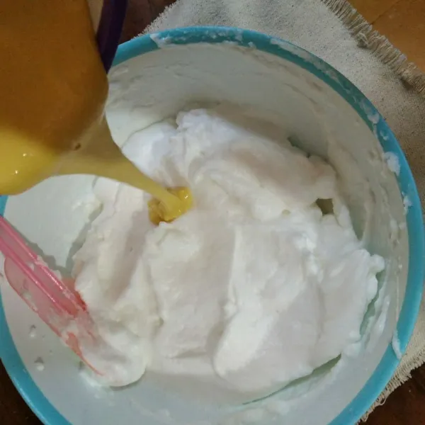 Masukkan adonan kuning telur ke dalam kocokan putih telur sambil diaduk hingga rata.