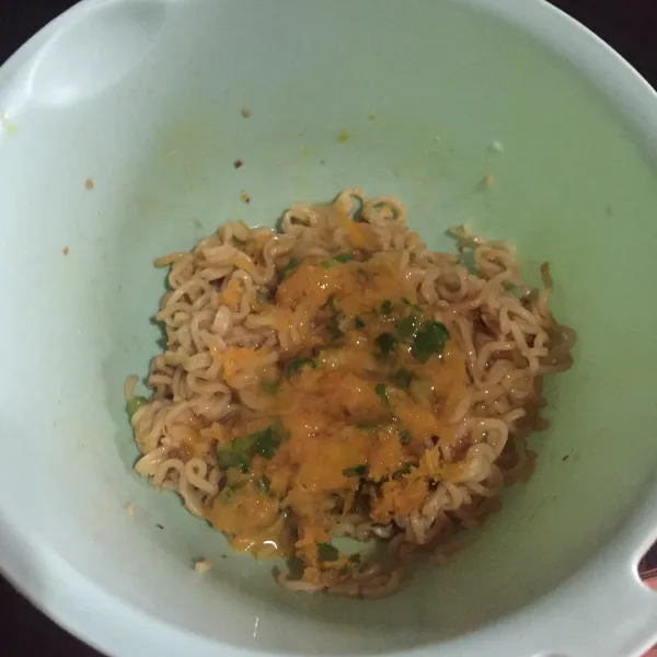 Masukan mie ke dalam wadah, tambahkan wortel parut, daun bawang, telur, bumbu mie, garam, dan totole, aduk rata