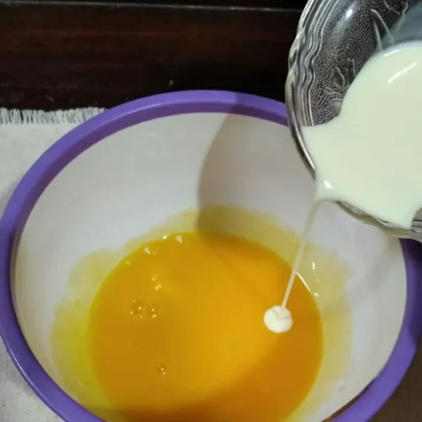 Masukkan susu cair ke dalam kuning telur, aduk rata.