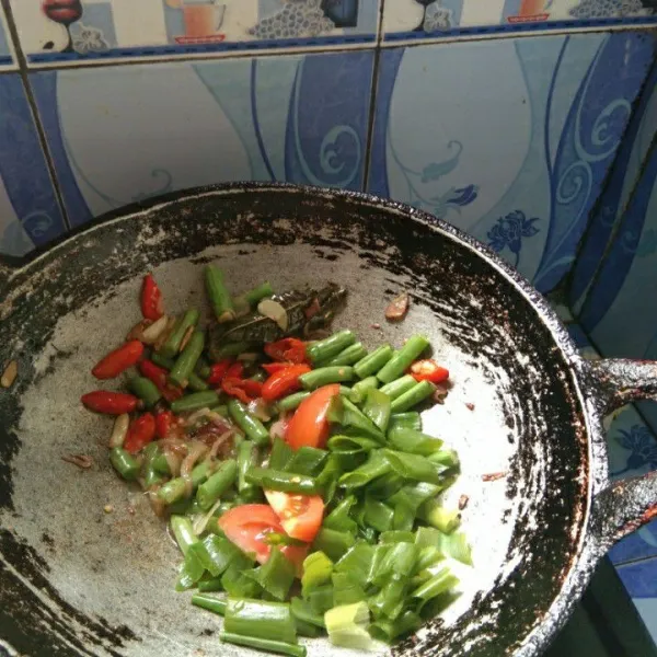 Tambahkan irisan bawang daun dan tomat, masak hingga bawang daun layu