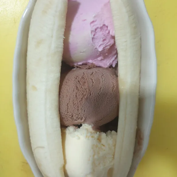 Skupkan es krim strawberry, cokelat dan vanilla ke dalam mangkok dan tambahkan pisang di kedua sisinya