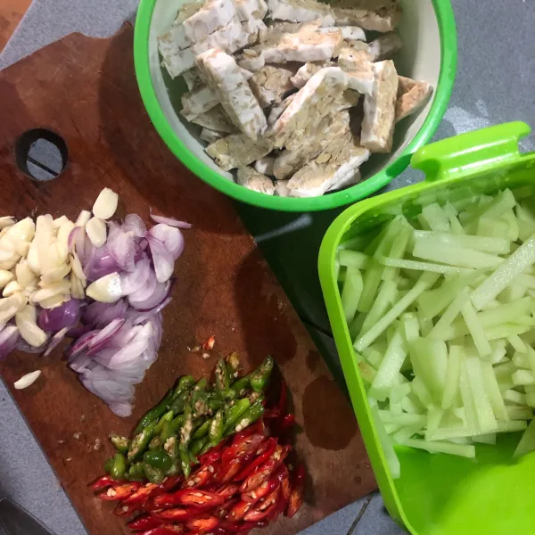 Siapkan bahan untum memasak. Iris cabai, bawang merah dan bawang putih. Potong labu siam dan tempe memanjang.