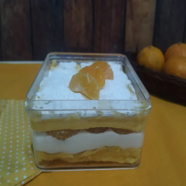 Ambil box. Tata dessert. Lapisan pertama cake. Lapisan kedua cream. Lapisan ketiga jeruk. Lapisan keempat cake lagi dan terakhir beri topping gula halus dan jeruk Mandarin baby. Sajikan