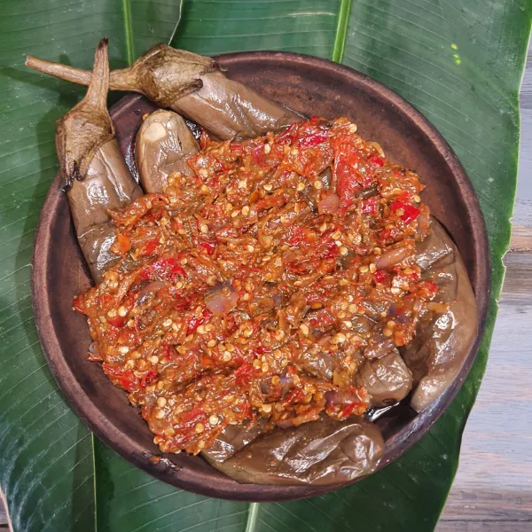 Tambahkan 100 ml air panas ke dalam ulegan. Air terserap oleh terong, apabila menginginkan agak lebih berkuah bisa ditambahkan air lagi. Sajikan.