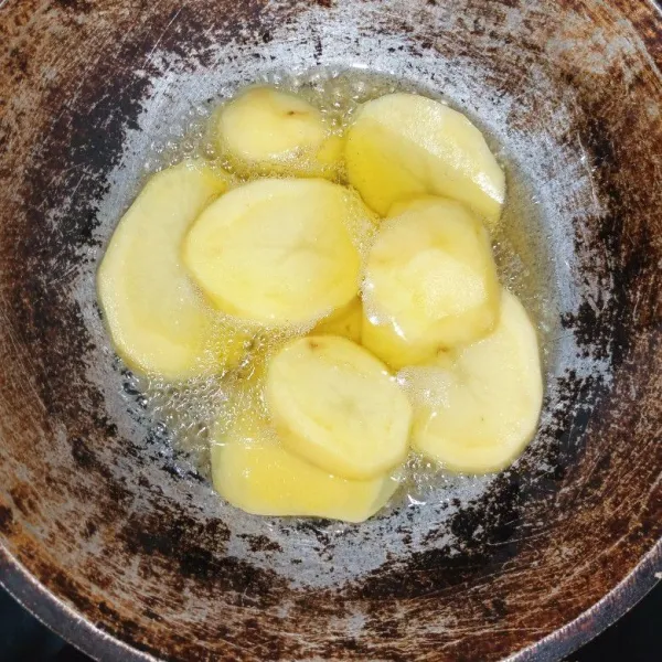 Potong kentang ketebalan 0,5 cm lalu cuci bersih. Panaskan minyak, goreng kentang hingga matang kuning kecokelatan.