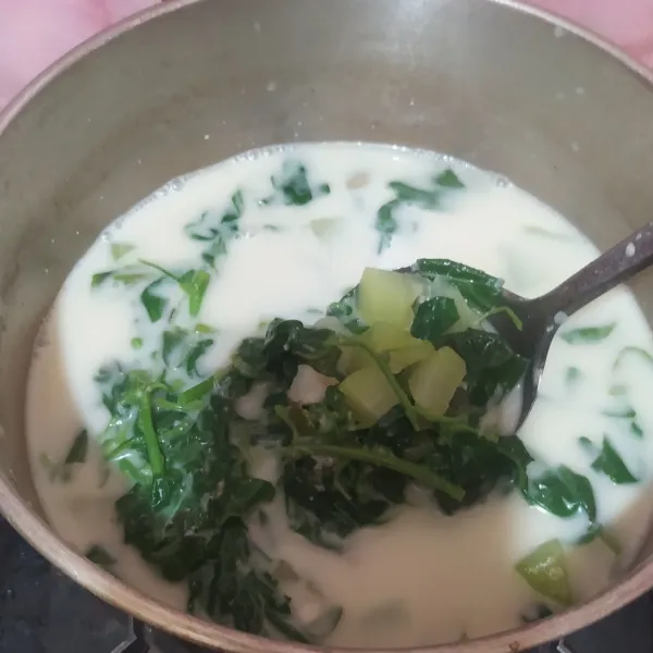 Setelah bayam empuk, masukkan santan, aduk rata, matikan kompor.
